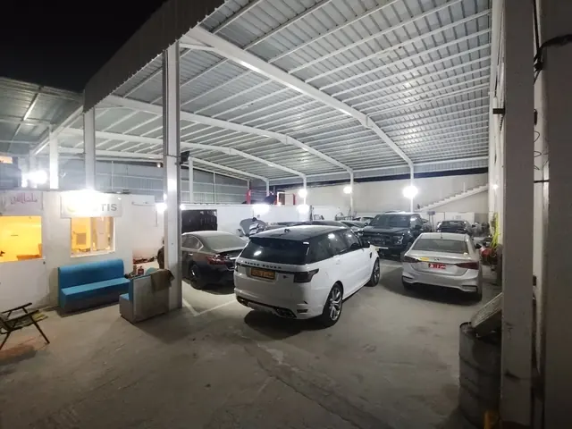 The covered workshop floor at night, with a Range Rover Sport and other customer cars