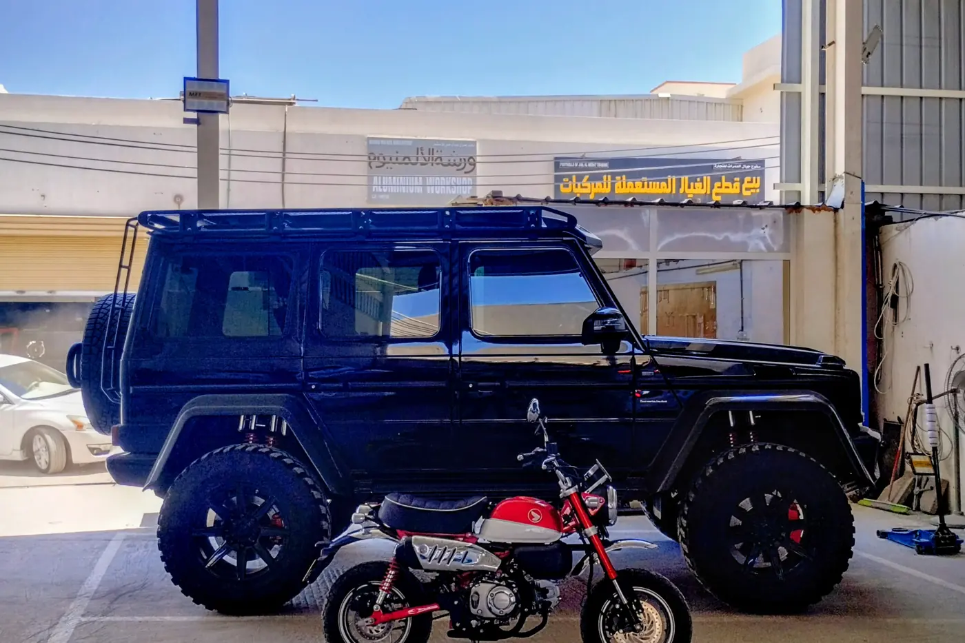 A black Mercedes-Benz G 500 4x4² and a red Honda Monkey at the Garage Lutis workshop